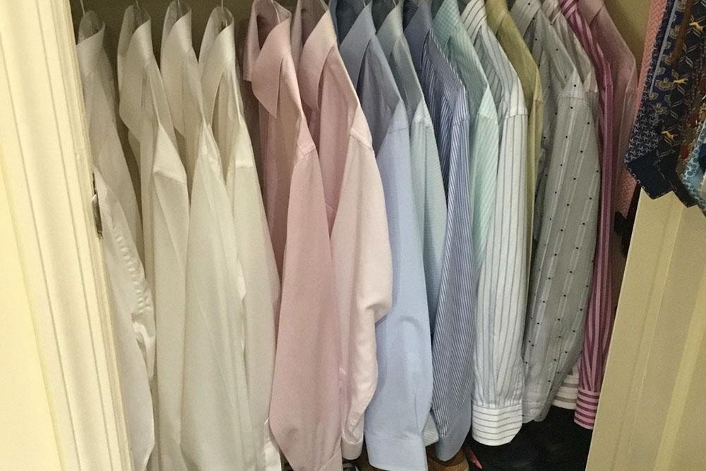 Color-sorted dress shirts neatly hung in an organized closet