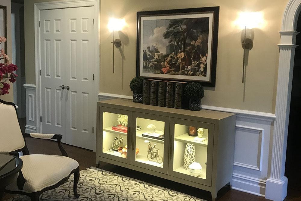 Elegant entryway with illuminated display cabinet and framed artwork