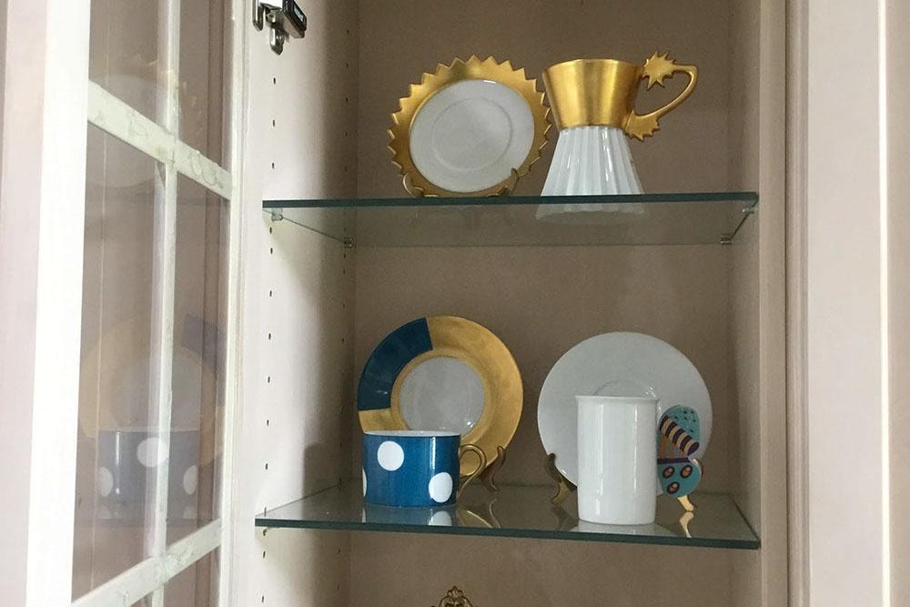 Glass display cabinet with gold-trimmed china and decorative dishware