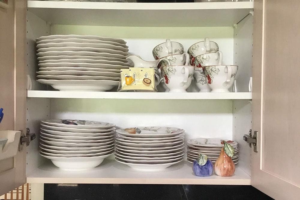 Neatly organized kitchen cabinet with stacked plates and cups