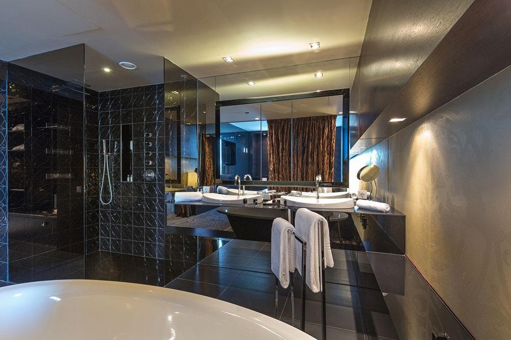 Luxury bathroom with black marble, dual sinks, and freestanding tub