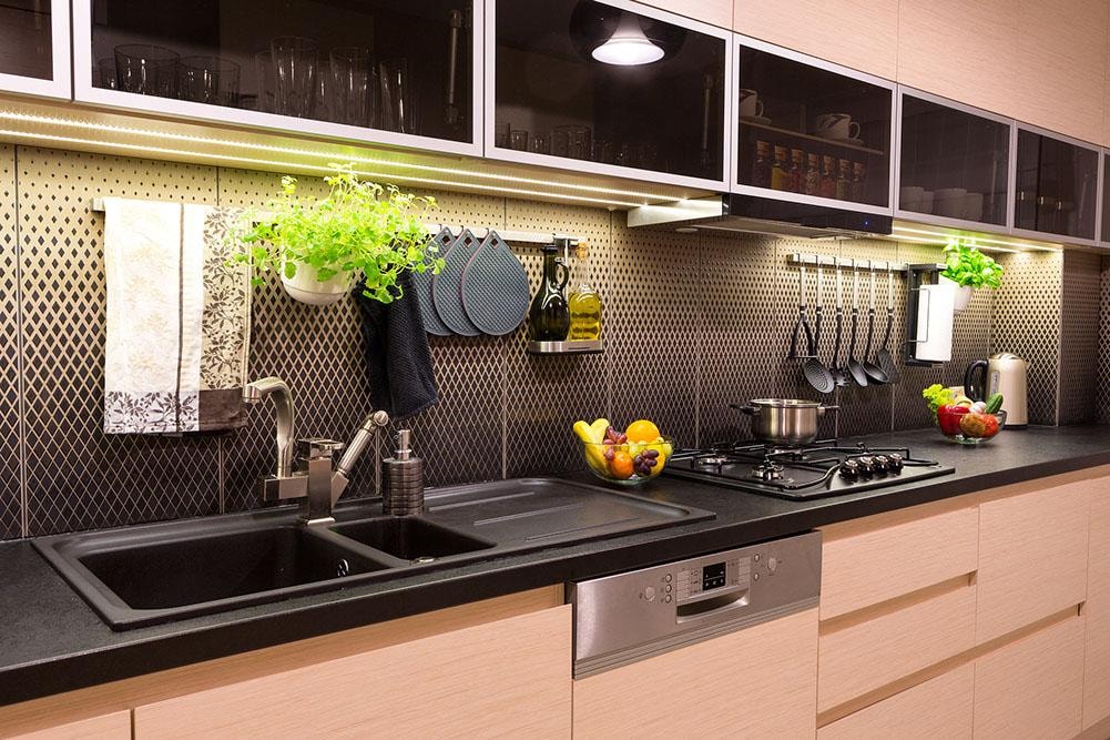 Modern kitchen with black countertops, LED lighting, and geometric backsplash