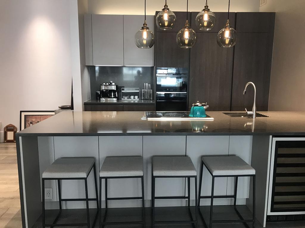 Modern kitchen with large gray island, pendant lighting, and bar seating