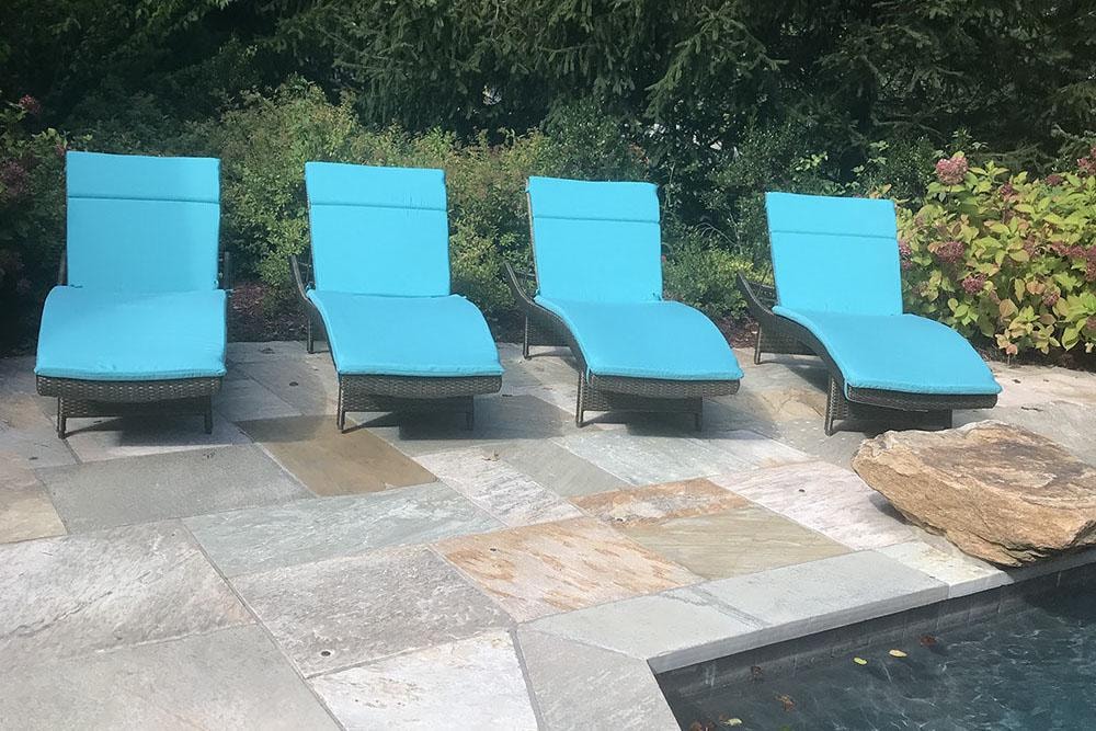 Poolside lounge chairs with blue cushions on stone patio